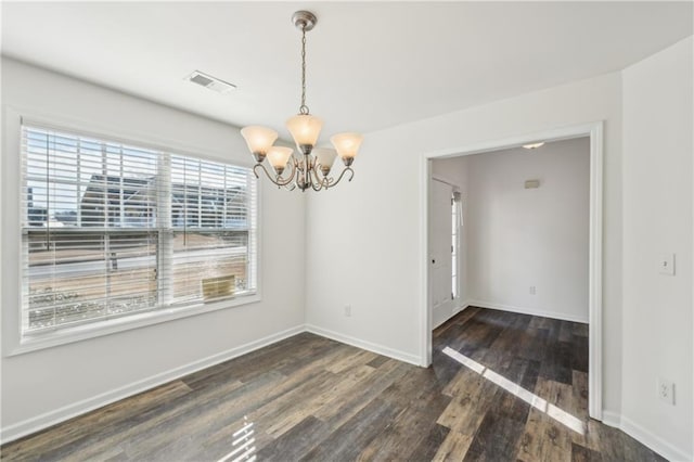 unfurnished dining area featuring an inviting chandelier, baseboards, visible vents, and wood finished floors