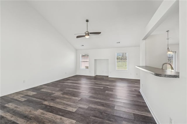 unfurnished living room with dark wood-style floors, lofted ceiling, baseboards, and ceiling fan with notable chandelier