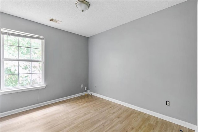 unfurnished room featuring plenty of natural light, light hardwood / wood-style floors, and a textured ceiling