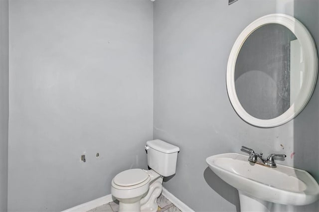 bathroom with toilet, sink, and tile patterned floors