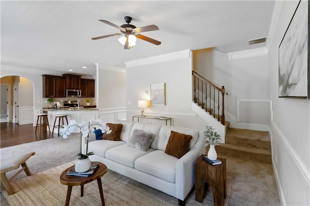 4249 Caveat Ct, Fairburn, GA 30213 - living area featuring ornamental molding, arched walkways, ceiling fan, a decorative wall, and stairs