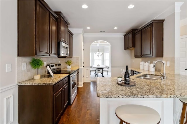 4249 Caveat Ct, Fairburn, GA 30213 - kitchen with stainless steel appliances, arched walkways, dark brown cabinets, crown molding, and recessed lighting