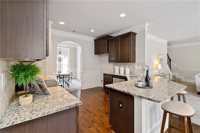 4249 Caveat Ct, Fairburn, GA 30213 - kitchen featuring a peninsula, crown molding, arched walkways, a breakfast bar area, and dark brown cabinets