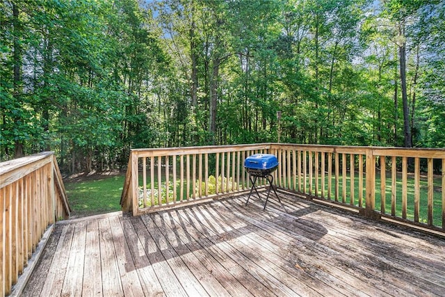 wooden terrace featuring a lawn and a grill