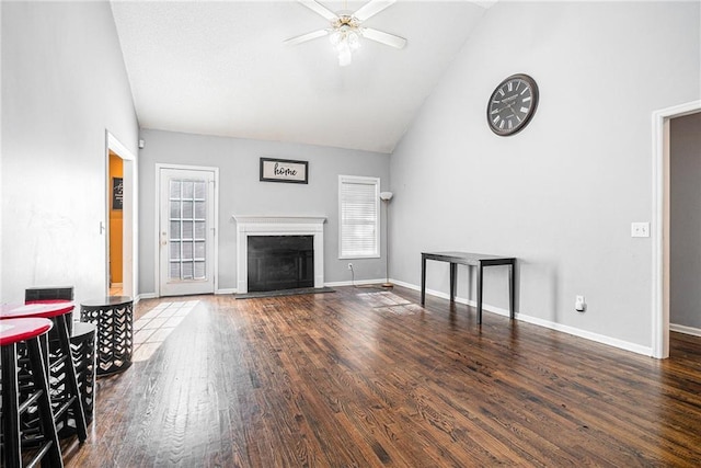 unfurnished living room with vaulted ceiling, healthy amount of natural light, a ceiling fan, wood finished floors, and a fireplace