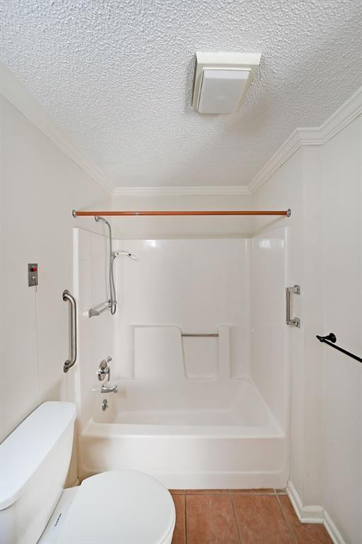 1800 Clairmont Lk Unit 326, Decatur, GA 30033 - bathroom with tub / shower combination, tile patterned flooring, a textured ceiling, crown molding, and toilet