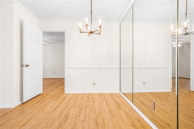 unfurnished dining area featuring baseboards, ornamental molding, wood finished floors, and a notable chandelier