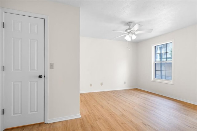 empty room featuring ceiling fan, light wood-style flooring, and baseboards