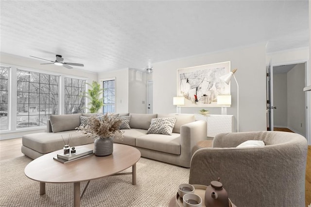 living area with ornamental molding, wood finished floors, and a ceiling fan