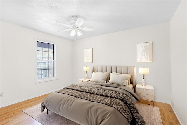 bedroom with light wood-style floors, ceiling fan, and baseboards