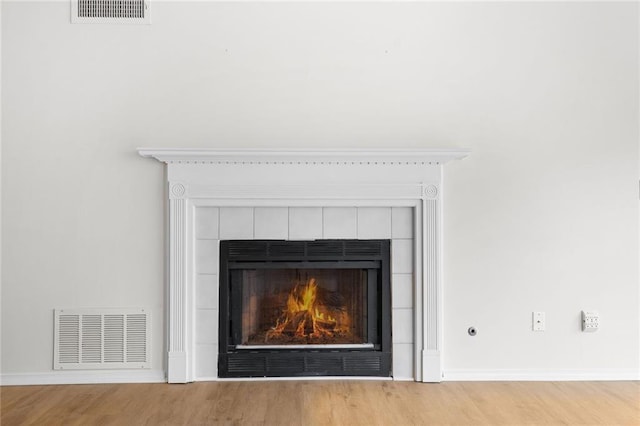 details featuring a fireplace, wood finished floors, visible vents, and baseboards