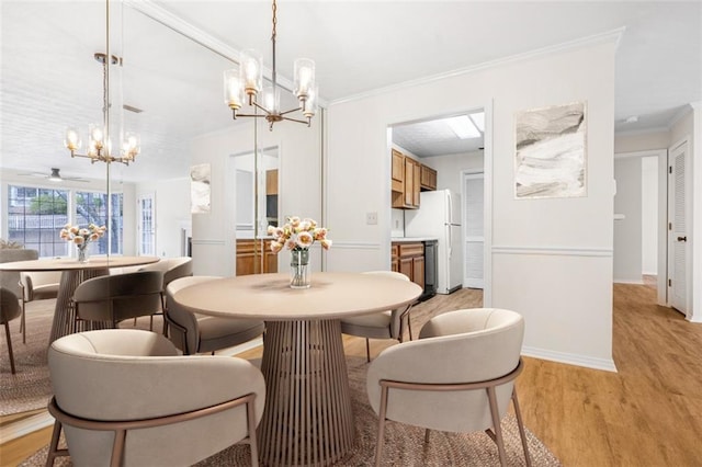 dining room featuring a chandelier, ornamental molding, light wood-style flooring, and baseboards