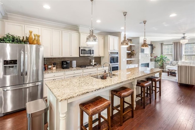 kitchen with pendant lighting, sink, an island with sink, and appliances with stainless steel finishes