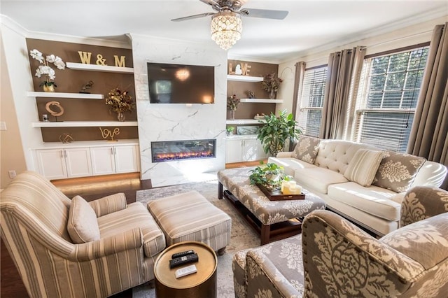 living room featuring built in shelves, ceiling fan, ornamental molding, and a fireplace