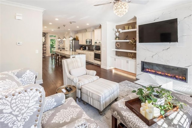 living room featuring ceiling fan, dark hardwood / wood-style flooring, ornamental molding, and a high end fireplace