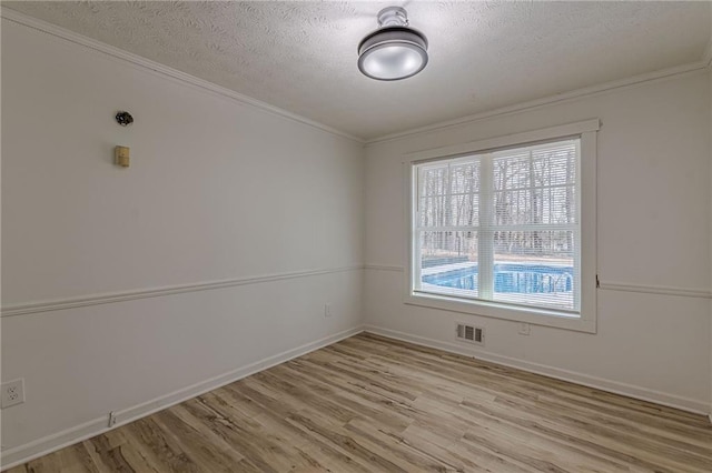7020 Camp Valley Rd, Riverdale, GA 30296 - empty room featuring a textured ceiling, light wood-style flooring, baseboards, visible vents, and ornamental molding