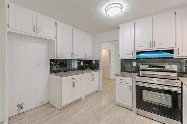 7020 Camp Valley Rd, Riverdale, GA 30296 - kitchen featuring decorative backsplash, electric range, light stone countertops, premium range hood, and white cabinetry