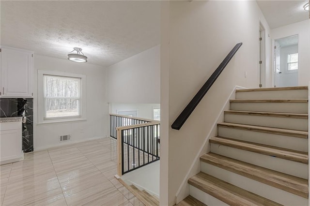 7020 Camp Valley Rd, Riverdale, GA 30296 - stairs with tile patterned floors, baseboards, a textured ceiling, and visible vents