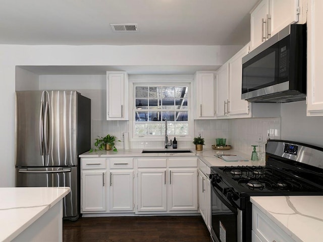 kitchen featuring stainless steel appliances, sink, white cabinets, and backsplash