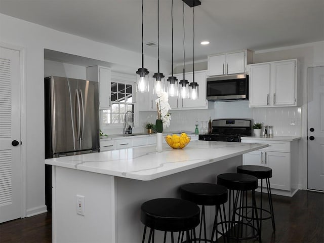 kitchen with pendant lighting, appliances with stainless steel finishes, a center island, and white cabinets