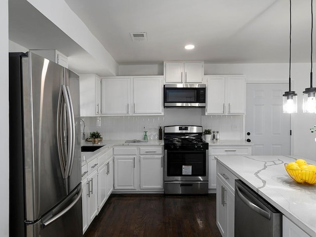 kitchen featuring sink, white cabinetry, stainless steel appliances, light stone countertops, and decorative light fixtures