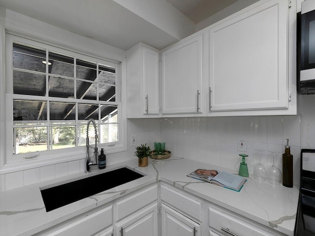 kitchen featuring tasteful backsplash, sink, and white cabinets