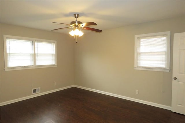 unfurnished room with visible vents, baseboards, dark wood-type flooring, and ceiling fan