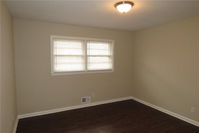 empty room with visible vents, baseboards, and dark wood-style flooring