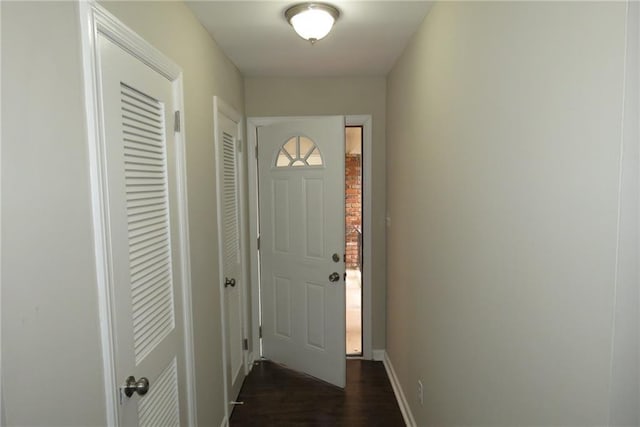 doorway featuring baseboards and dark wood-style flooring