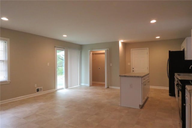 kitchen featuring visible vents, black appliances, a center island, recessed lighting, and white cabinetry