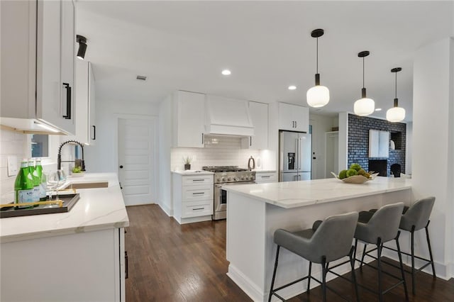 kitchen featuring white cabinets, premium appliances, dark wood-style floors, custom exhaust hood, and a sink