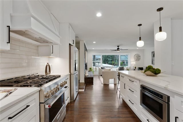 kitchen featuring light stone counters, dark wood finished floors, stainless steel appliances, open floor plan, and premium range hood