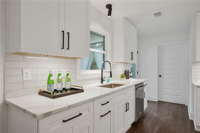 kitchen with light stone counters, dark wood-style flooring, a sink, white cabinetry, and dishwasher