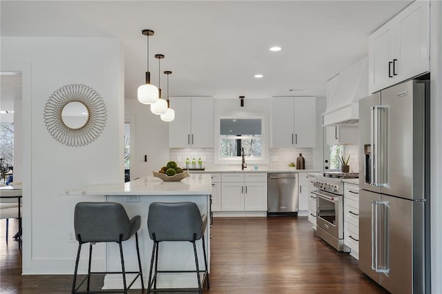 kitchen featuring high quality appliances, a breakfast bar, custom exhaust hood, light countertops, and backsplash