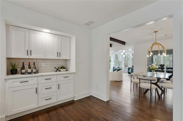 bar with a notable chandelier, visible vents, baseboards, decorative backsplash, and dark wood-style floors