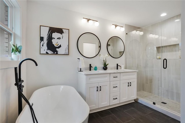 bathroom with double vanity, a shower stall, a sink, and a freestanding bath