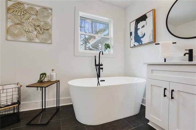 bathroom with a freestanding tub, vanity, baseboards, and tile patterned floors