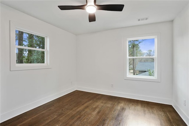 unfurnished room featuring dark wood-type flooring, visible vents, ceiling fan, and baseboards