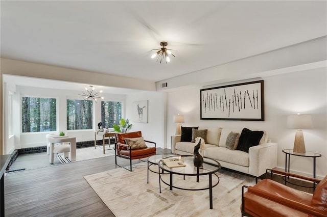 living area with a chandelier, visible vents, baseboards, and wood finished floors