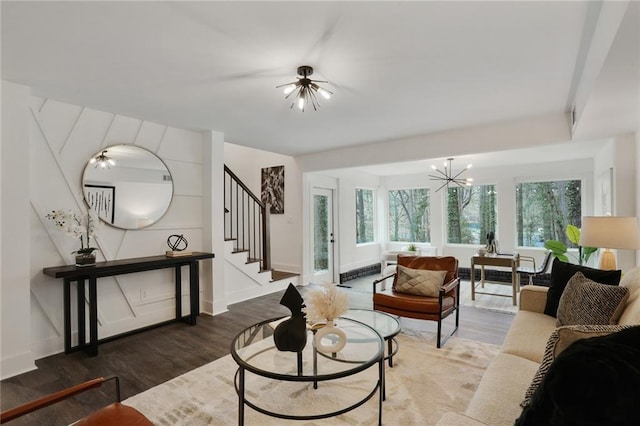 living room featuring stairs, baseboards, wood finished floors, and an inviting chandelier