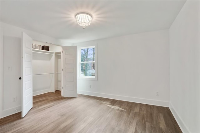 unfurnished bedroom featuring a closet, wood finished floors, and baseboards