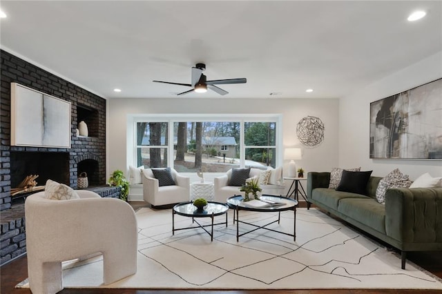 living area with a brick fireplace, a ceiling fan, and recessed lighting