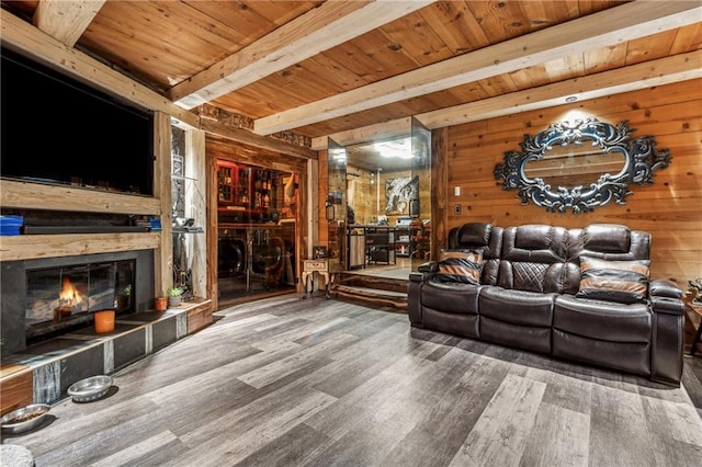 living room featuring wood walls, wooden ceiling, a tile fireplace, hardwood / wood-style flooring, and beamed ceiling