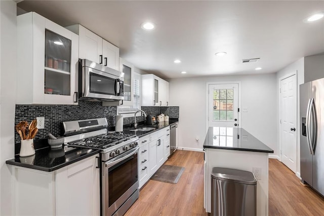 2189 Gordon Cir SE, Smyrna, GA 30080 - kitchen featuring stainless steel appliances, a sink, glass insert cabinets, backsplash, and light wood-style flooring