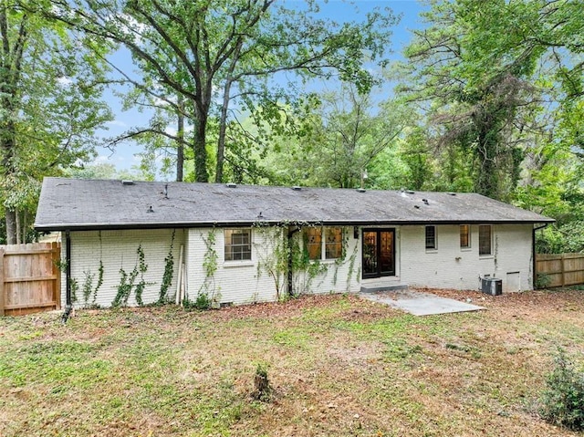 rear view of property featuring brick siding, fence, a lawn, and central AC unit