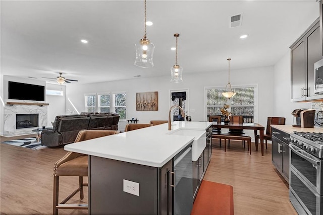 kitchen with decorative light fixtures, stainless steel appliances, light countertops, visible vents, and light wood-style floors