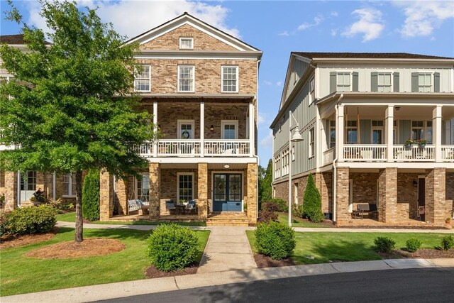 view of front facade with a front lawn, a balcony, and a porch