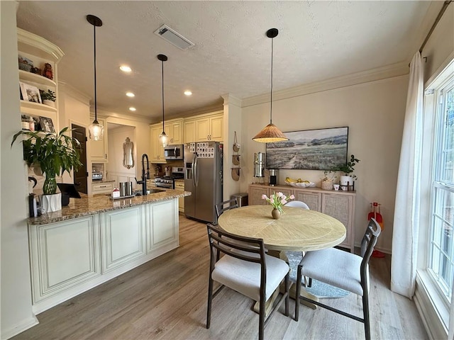 kitchen with visible vents, light wood-style flooring, light stone counters, a peninsula, and stainless steel appliances