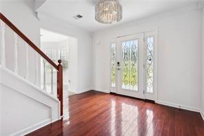 foyer entrance with wood finished floors, a notable chandelier, baseboards, and stairs