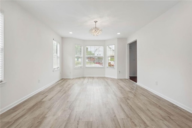 empty room featuring light wood-style floors, baseboards, a chandelier, and recessed lighting